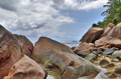 Rock formations on beach against sky