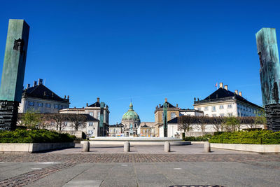 Buildings in city against clear blue sky