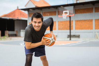 Portrait of man playing with basketball