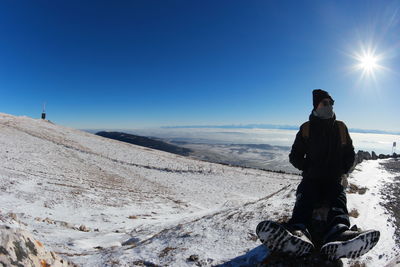 Rear view of man standing on snow covered landscape