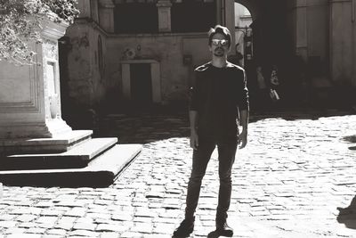 Portrait of young man standing against building