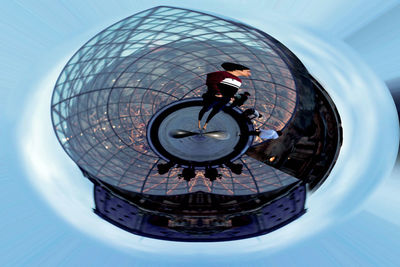 Digital composite image of man with bicycle wheel against sky