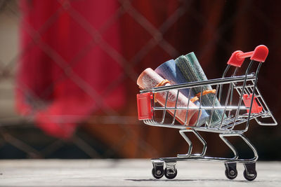 Close-up of rolled paper currency in small shopping cart on table