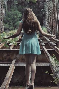 Rear view of woman standing on abandoned bridge