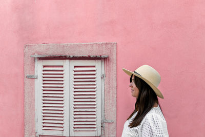 Young woman standing in front of pink wall, white window, minimalism, minimalist architecture.