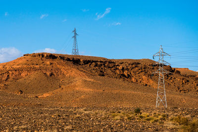 Electricity pylon on land against sky