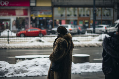 Rear view of woman on street in city during winter