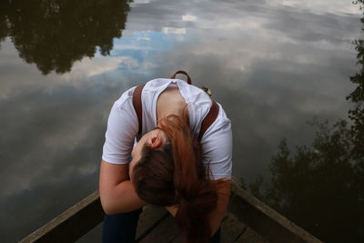 Rear view of young woman by railing against sky