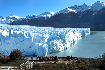 Group of people on snowcapped mountain against sky