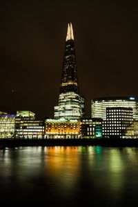 Illuminated shard london bridge by lake at night