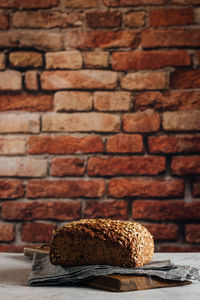 Close-up of bread on table against brick wall
