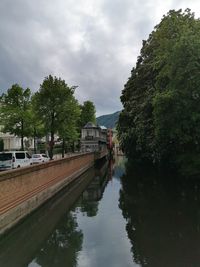 Canal amidst trees against sky