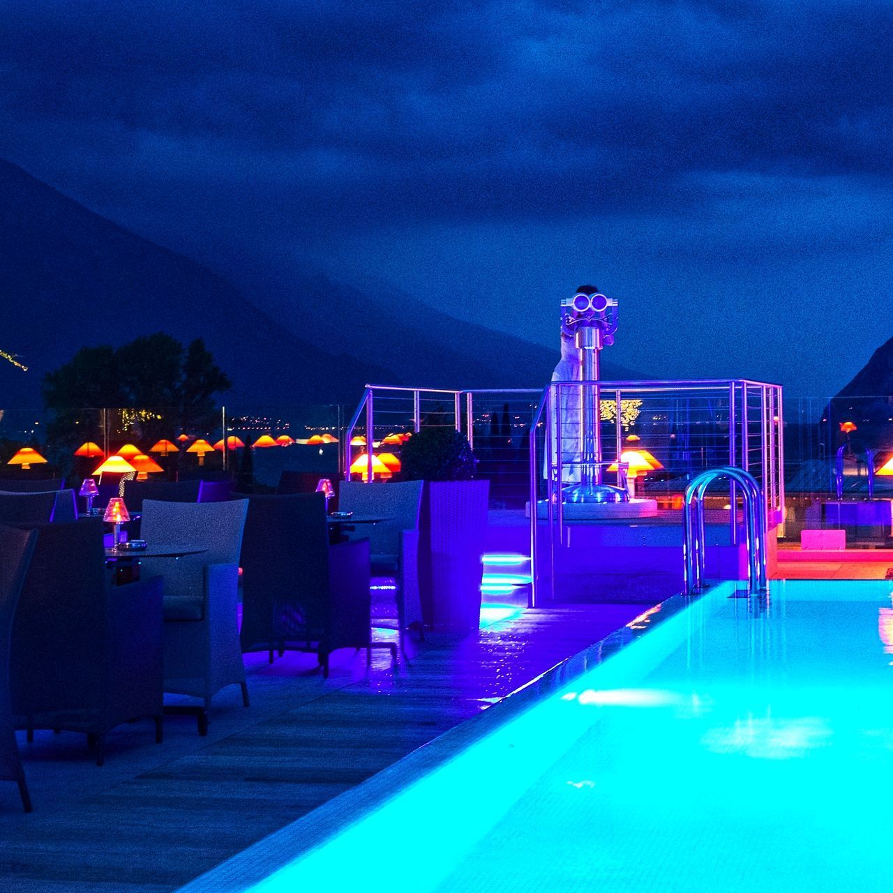 ILLUMINATED CHAIRS BY SWIMMING POOL AT NIGHT