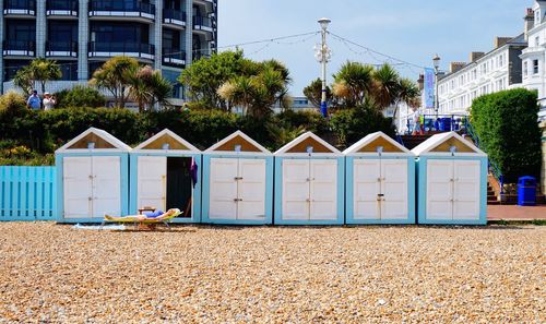 Woman sunbathing by huts at beach