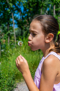 Side view of woman looking at dandelion