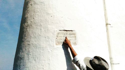 Low angle view of hand holding text against wall