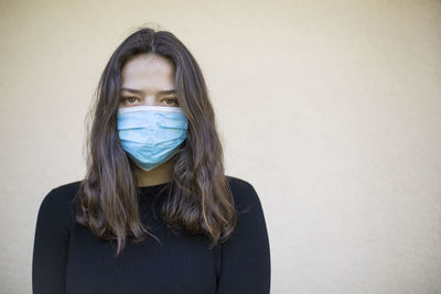 Portrait of young woman against wall