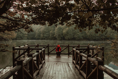 Man standing on pier by footbridge