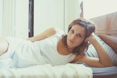 Portrait of young woman relaxing on bed at home