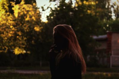 Rear view of woman standing against trees