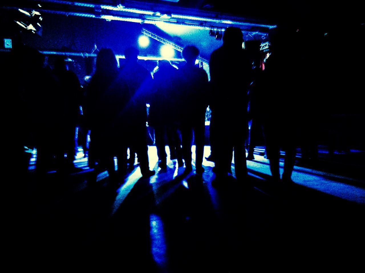 men, night, lifestyles, indoors, illuminated, person, leisure activity, large group of people, arts culture and entertainment, rear view, standing, music, group of people, togetherness, medium group of people, dark, blue, crowd, silhouette