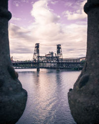 Bridge over river in city against sky during sunset