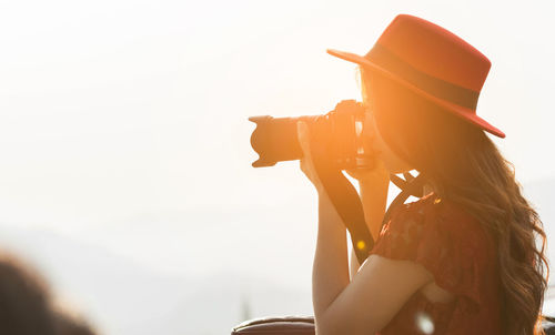 Midsection of woman photographing against sky