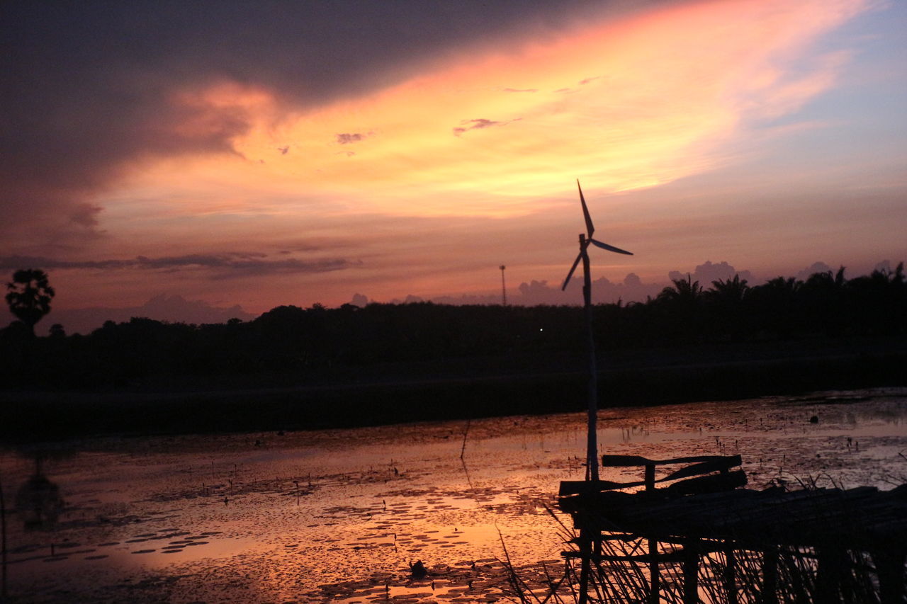 SILHOUETTE WINDMILLS ON LANDSCAPE AGAINST ORANGE SKY