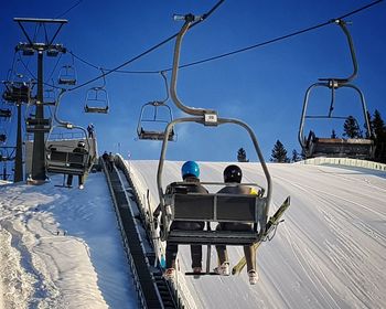 Rear view of ski lift against snowcapped mountain