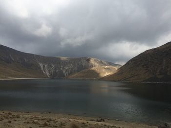 Scenic view of lake and mountains against cloudy sky