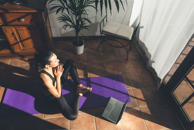 Young caucasian brunette woman practicing yoga at home sitting in lotus pose.