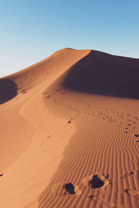 Sand dunes in desert against clear sky