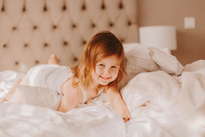 Cute little girl enjoying early morning on bed at home