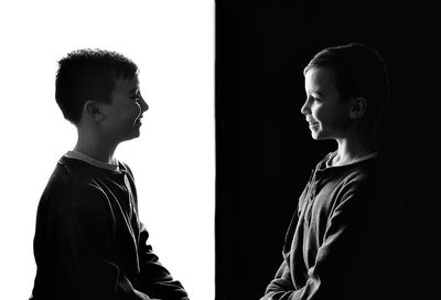 Smiling boys holding hands standing against black and white background