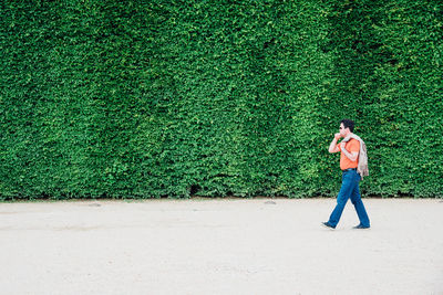 Full length side view of man walking by plants in park