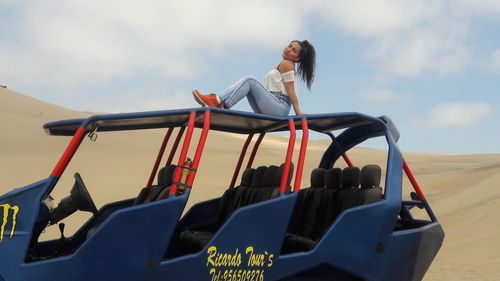 Low angle view of woman sitting against blue sky