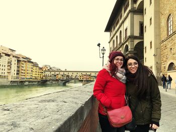 Woman standing by canal in city