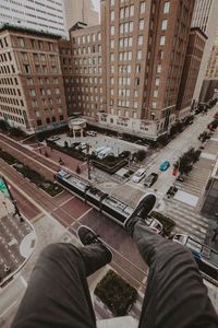 Low section of man sitting on building terrace in city