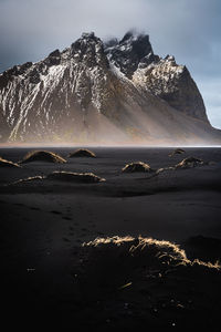 Scenic view of sea by mountains against sky during winter