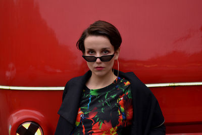 Portrait of young woman standing against red wall