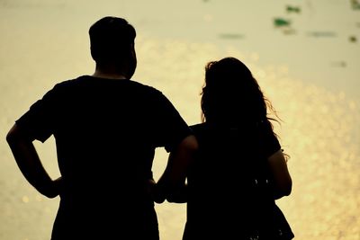 Silhouette couple standing against sky during sunset