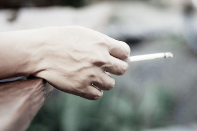 Close-up of hand holding cigarette