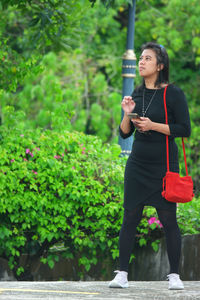 Full length of woman standing against plants