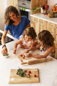 Mother and daughters preparing food in kitchen at home
