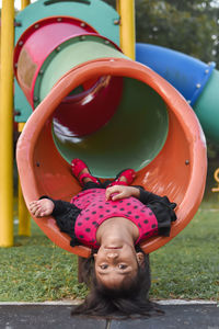 Portrait of girl lying on slide in playground