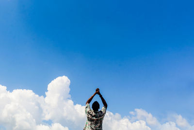 Low angle view of person against blue sky