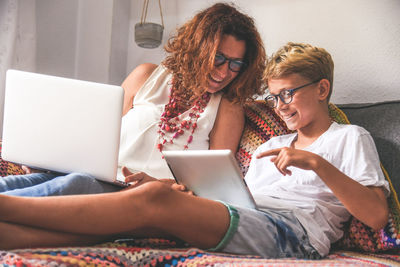 Smiling mother and son using technologies at home