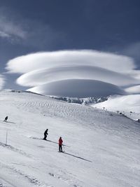 People skiing on snow covered mountain against sky