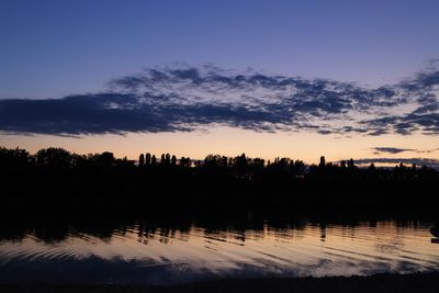 Silhouette trees by lake against sky during sunset