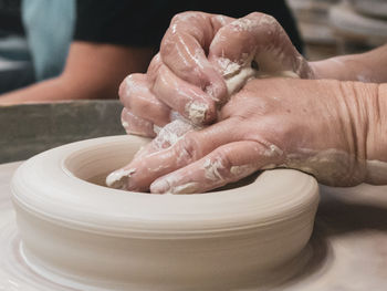 Cropped hands of man shaping mud on pottery wheel